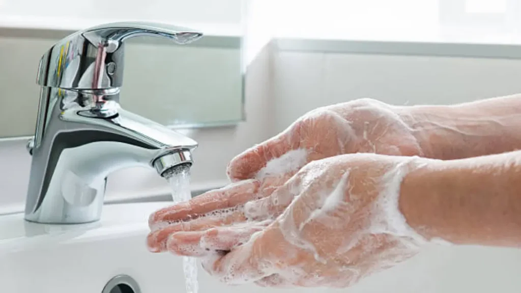 Person washing hands with soap and water to prevent viral hepatitis and protect liver
